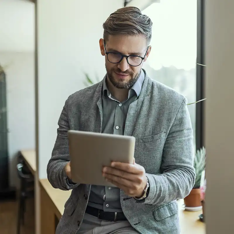 Business man sitting on an office counter using a tablet